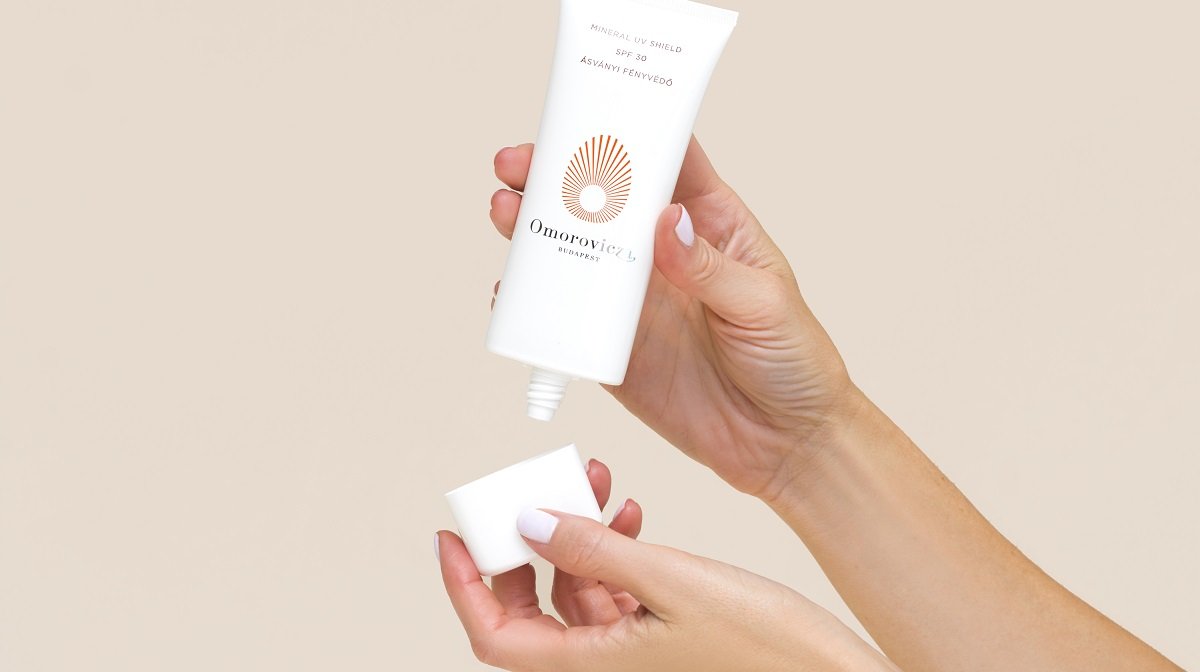 Woman holding a tube of Omorovicza's Mineral UV Shield Sunscreen with SPF 30.