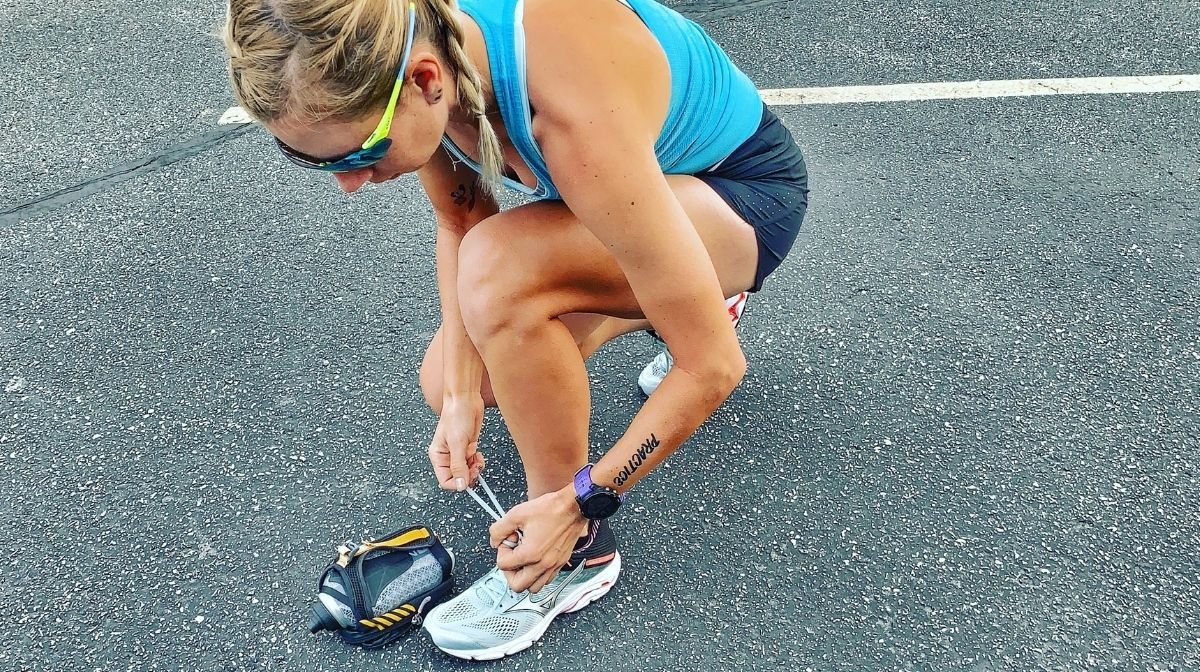 Sponsored Klean Athlete runner tying her shoelace out on the tracks.