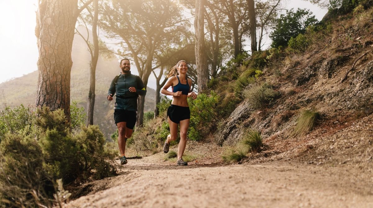 A female and male athlete run through the woods after monitoring their vitamin D levels