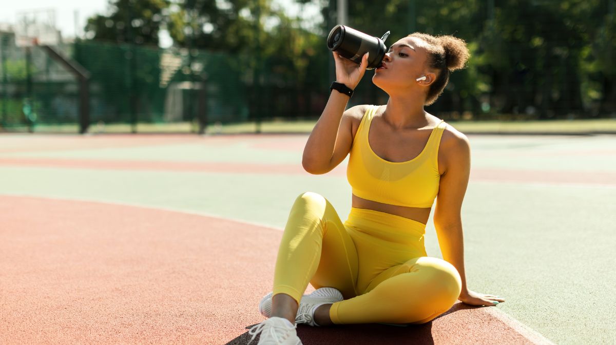 A young woman drinks pre-workout to support her athletic performance.