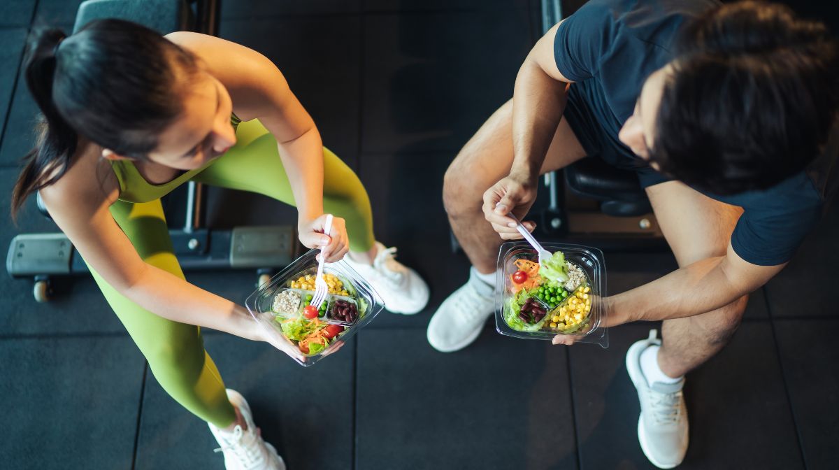 A couple eat their post-workout meal at the gym.