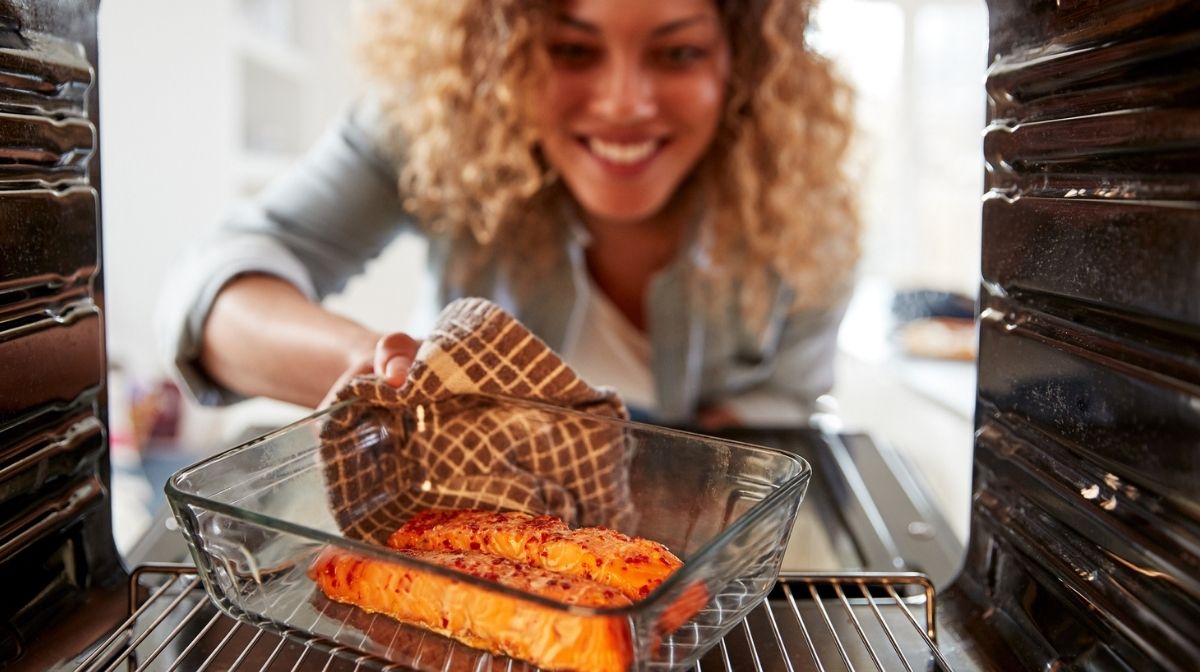 woman cooking salmon, which is rich in omega-3