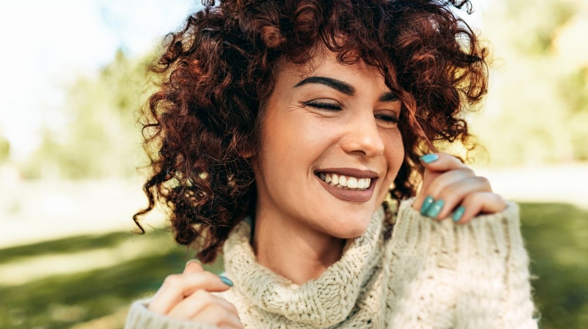 close-up of happy woman with naturally curly hair and painted nails