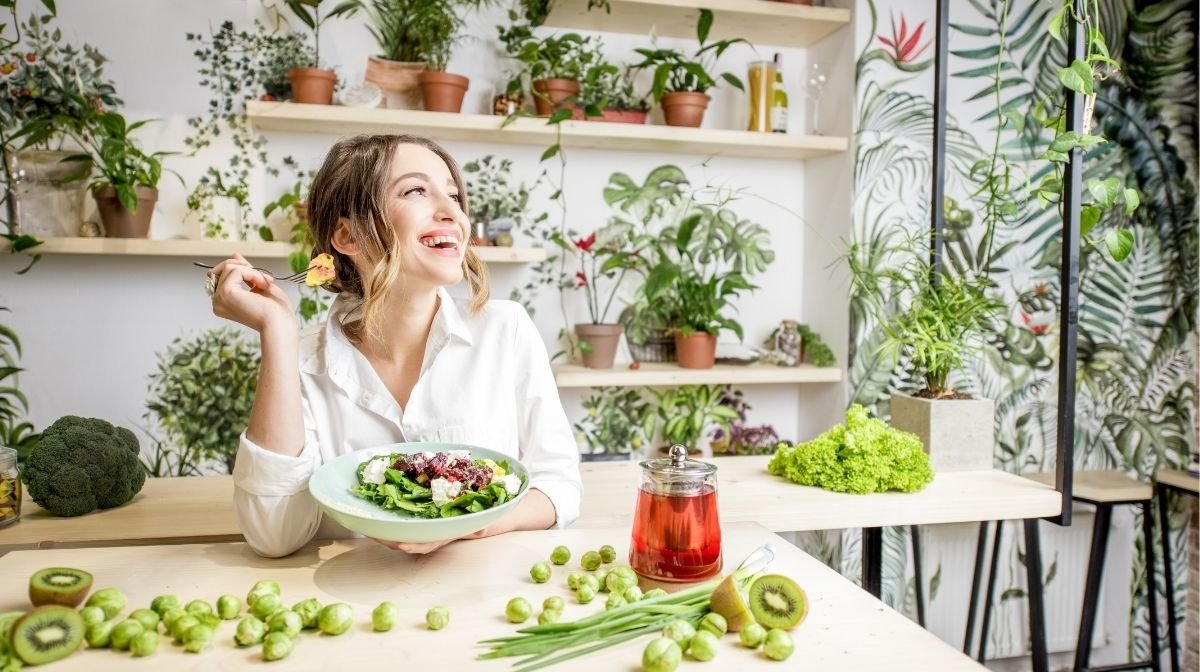 woman eating vegan food surrounded by plants