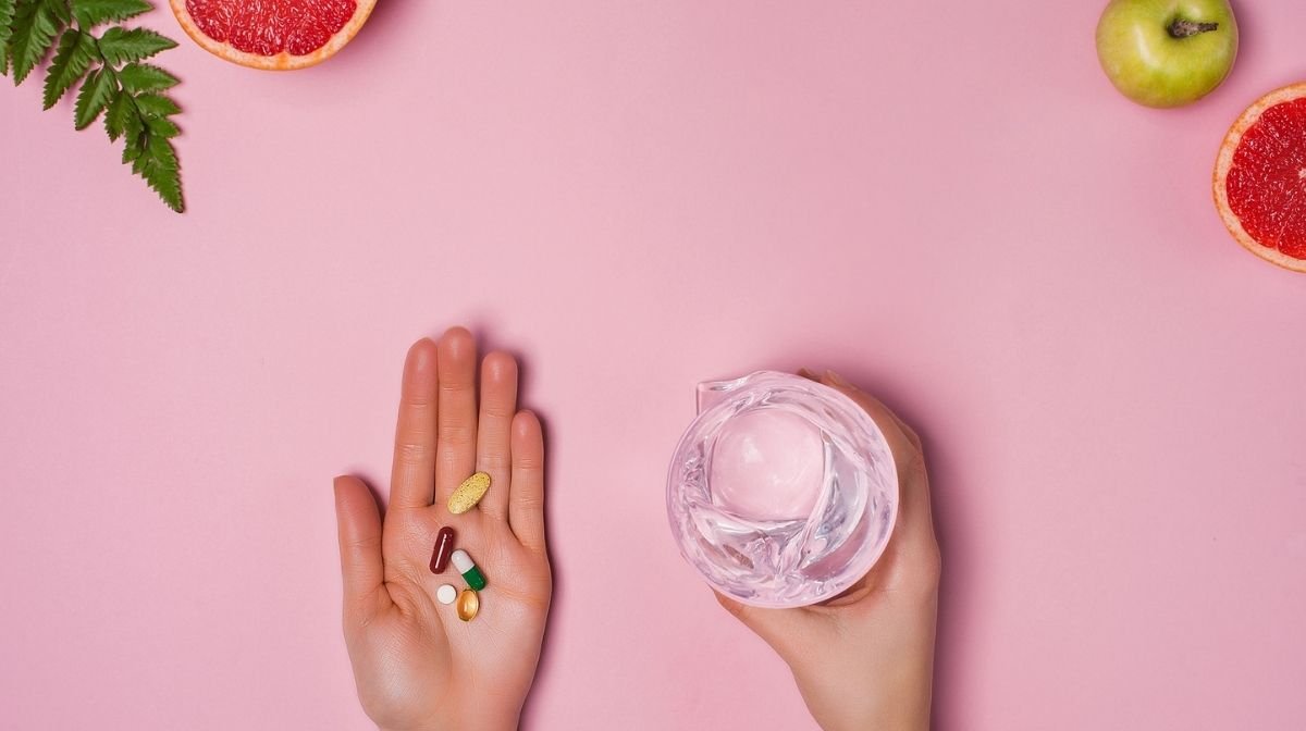 woman with a handful of vitamins and a glass of water