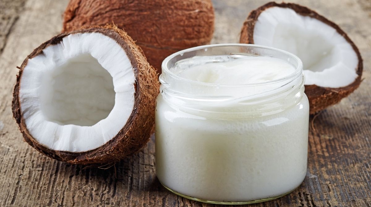 Fresh coconuts and a jar of coconut oil on a wooden table