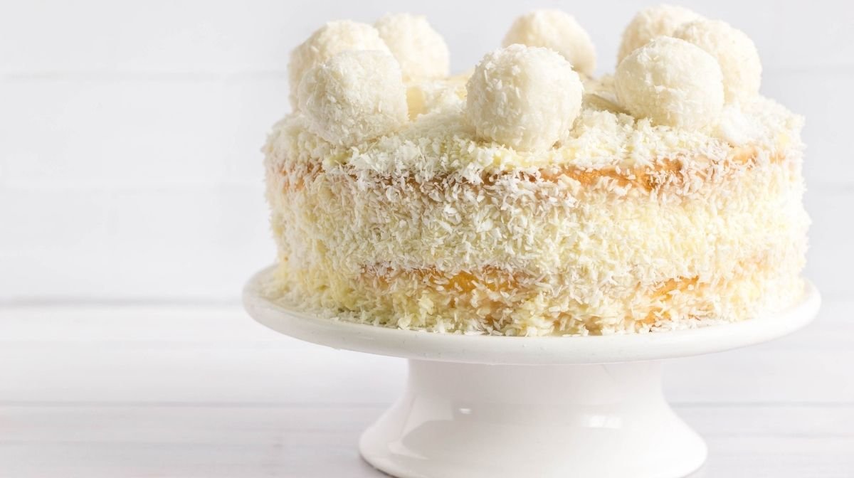 White coconut cake with coconut balls on top.