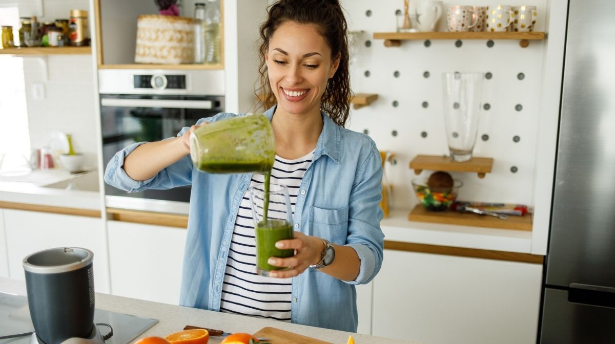 woman pouring a green smoothie