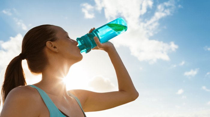 women drinking water from a bottle in a sunny day