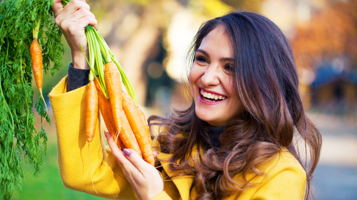 woman in orange holding carrots in a sunny day
