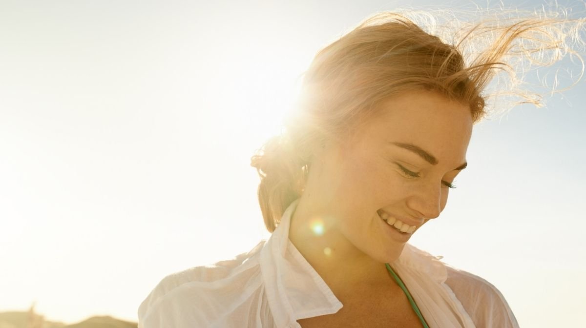 girl smiling outside with the sun shining on her