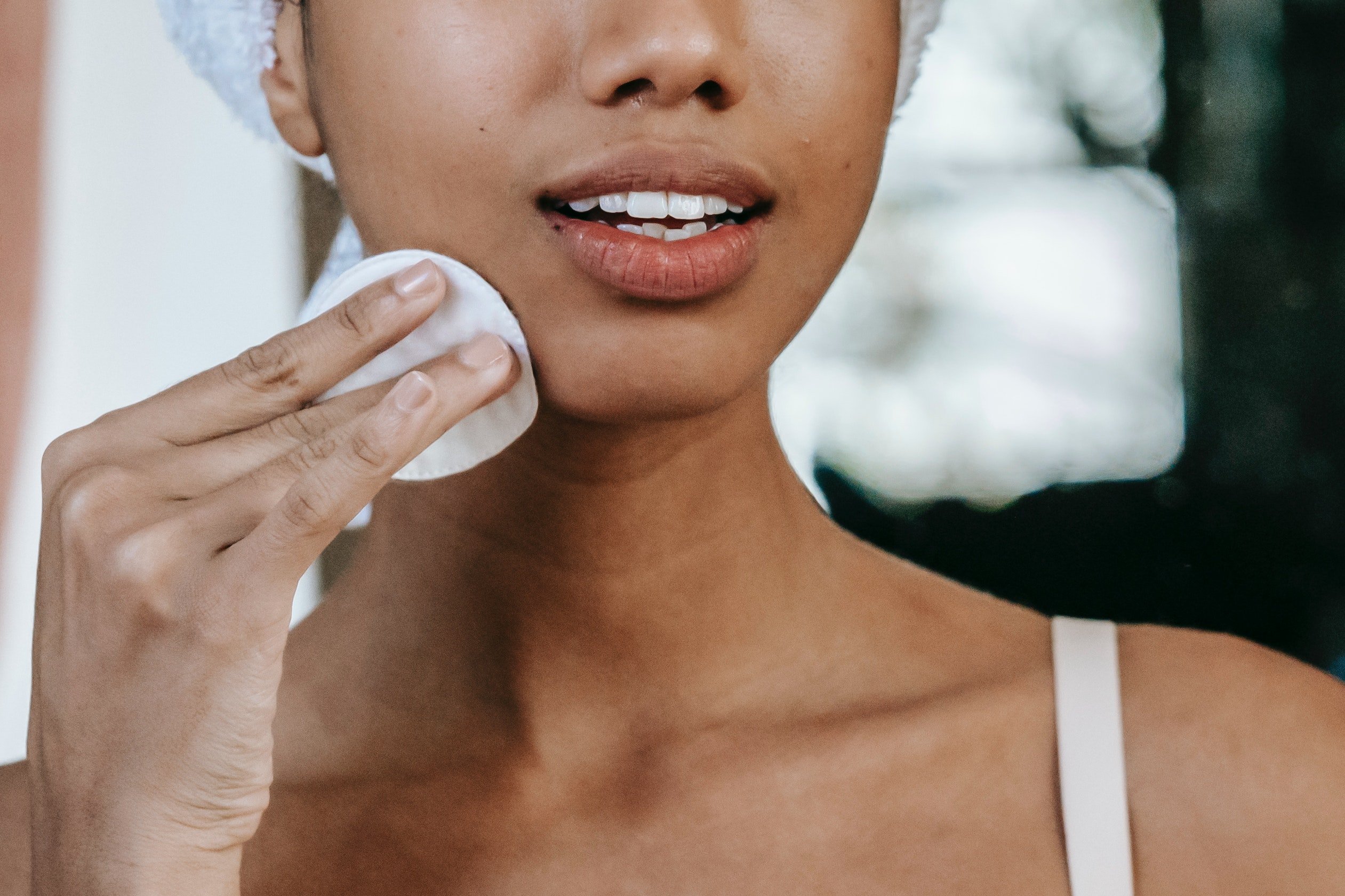 woman exfoliating face with chemical exfoliant on cotton round