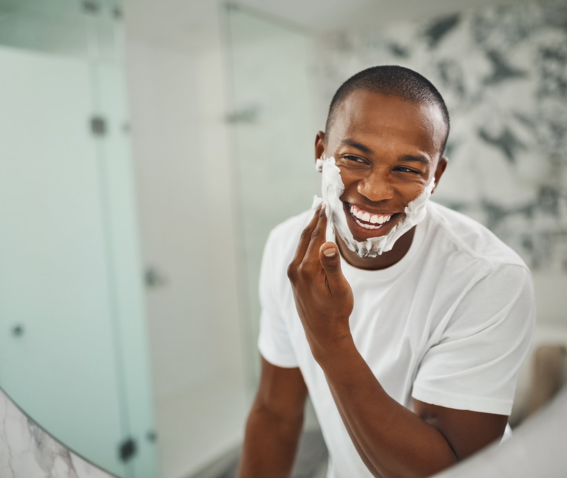 Man applying Perricone MD CBD sensitive skin shaving cream to his face in the mirror