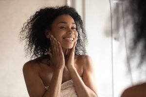 woman looking in mirror and touching face