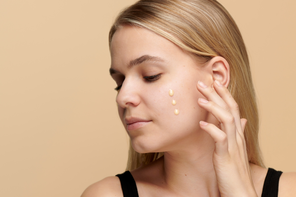 Young woman applying vitamin C serum on cheek, showing skincare benefits for radiant skin