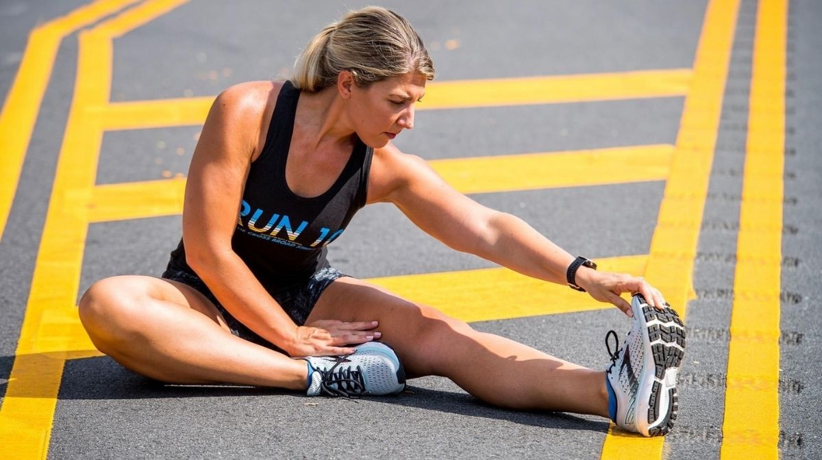Athlete sat on the ground, stretching left leg