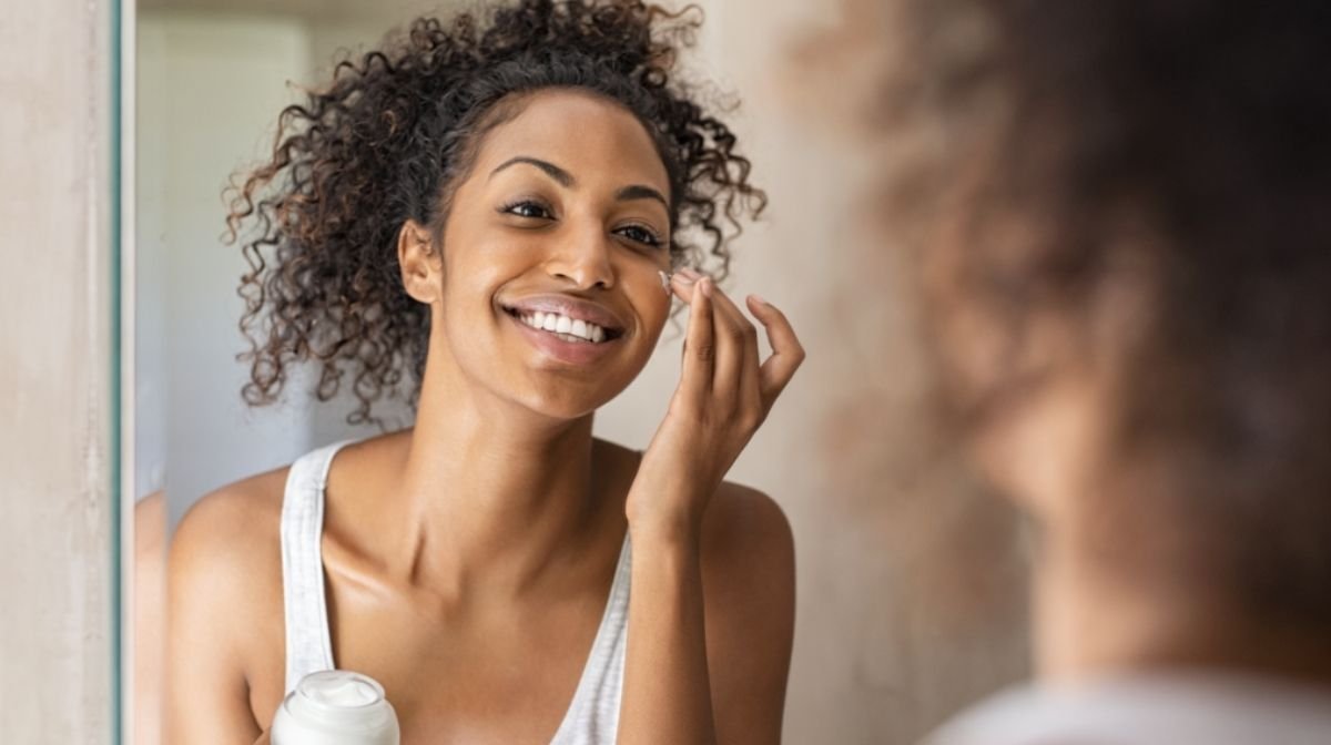 woman applying skincare in mirror