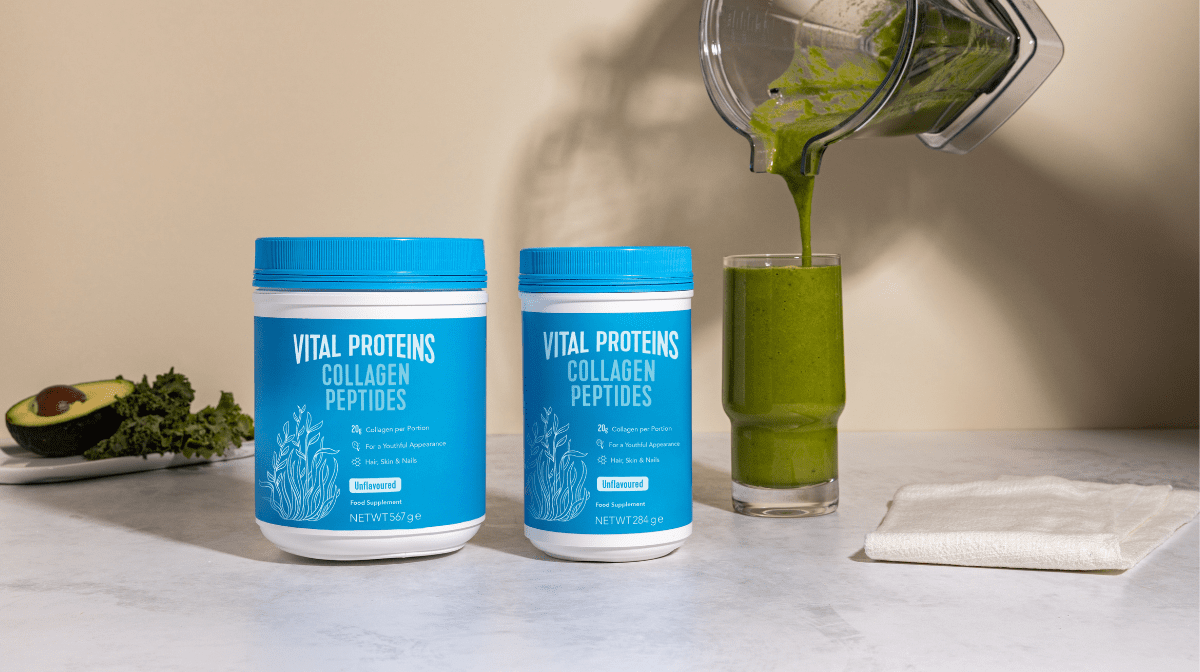 Vital Proteins Collagen Peptides Tins standing on the table next to a green smoothie.