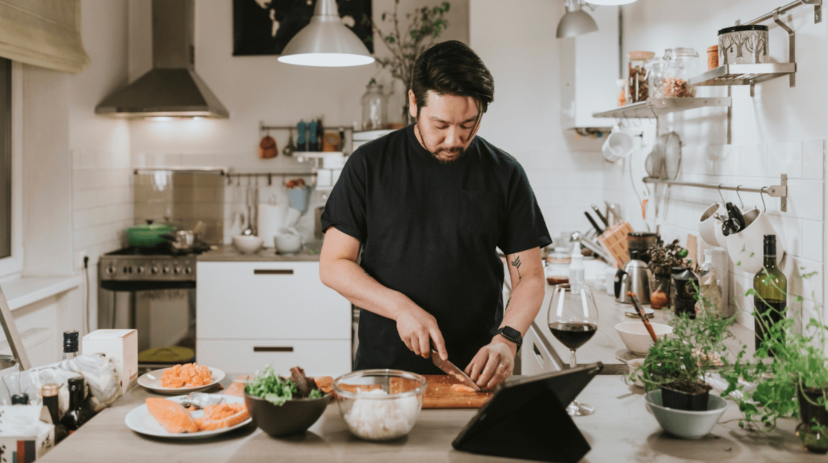 Asian man cutting up fresh salmon in kitchen