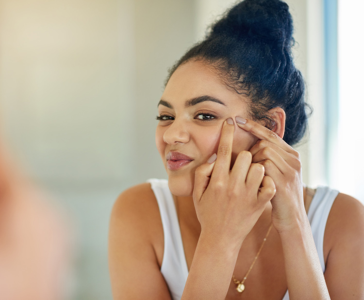 woman squeezing spot on face