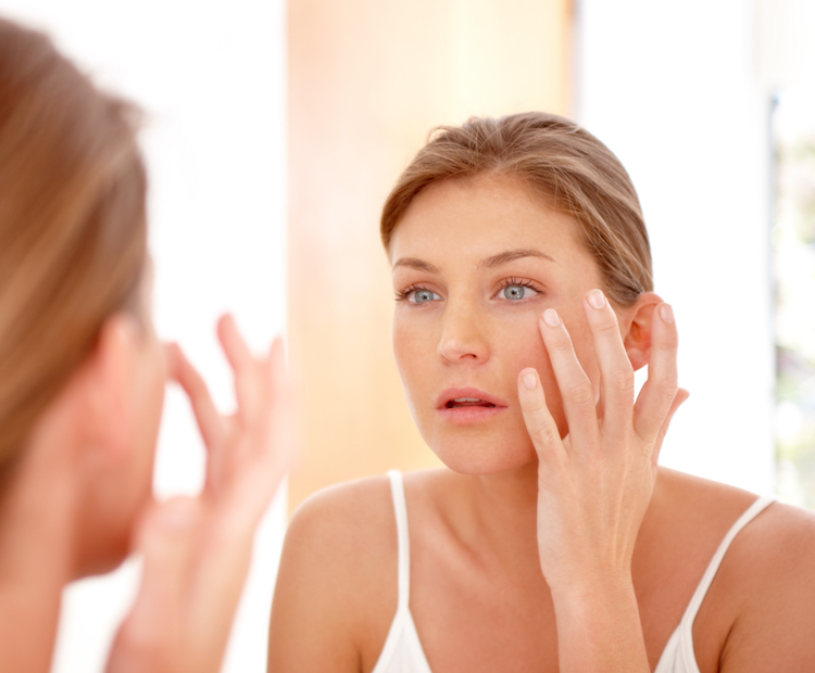 woman looking at her skin in mirror