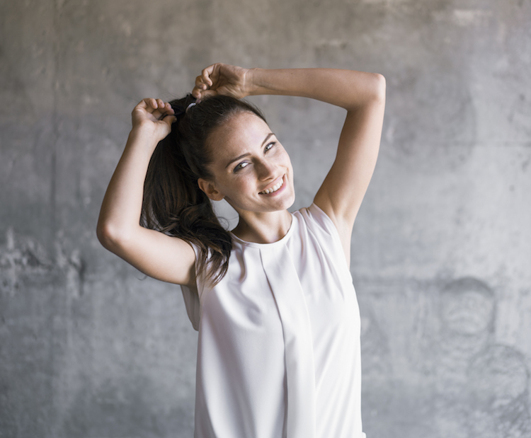 woman tying hair in ponytail