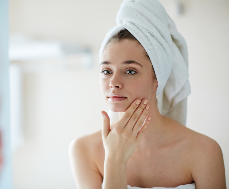 woman looking at skin in mirror