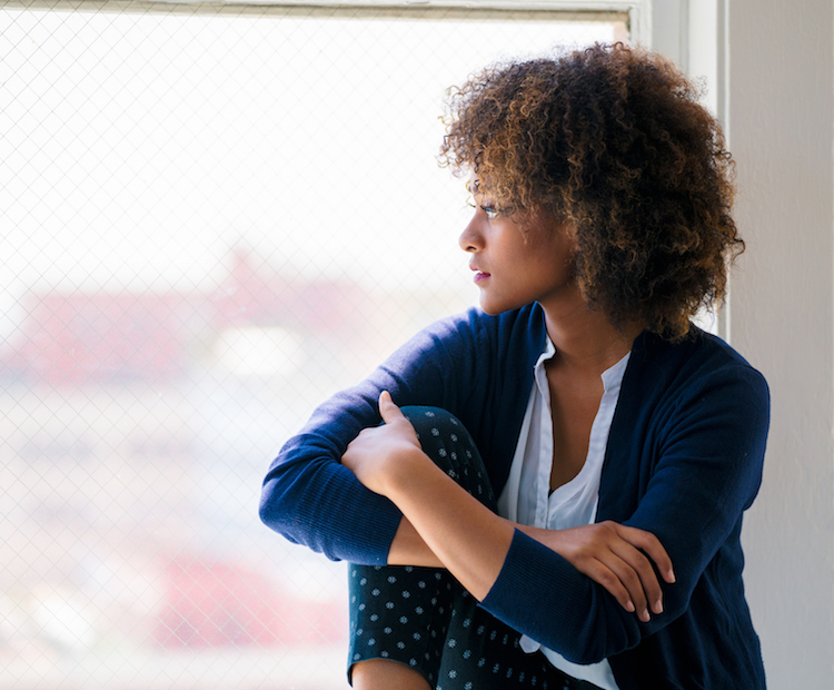 woman touching elbows looking out window