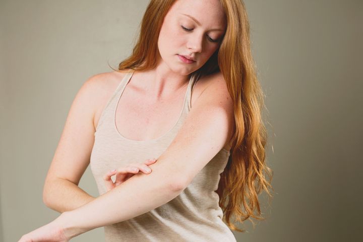 woman inspecting the skin on her arm