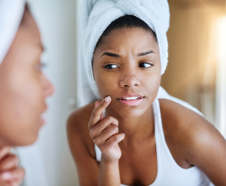 Woman looking at and touching face in the mirror 2