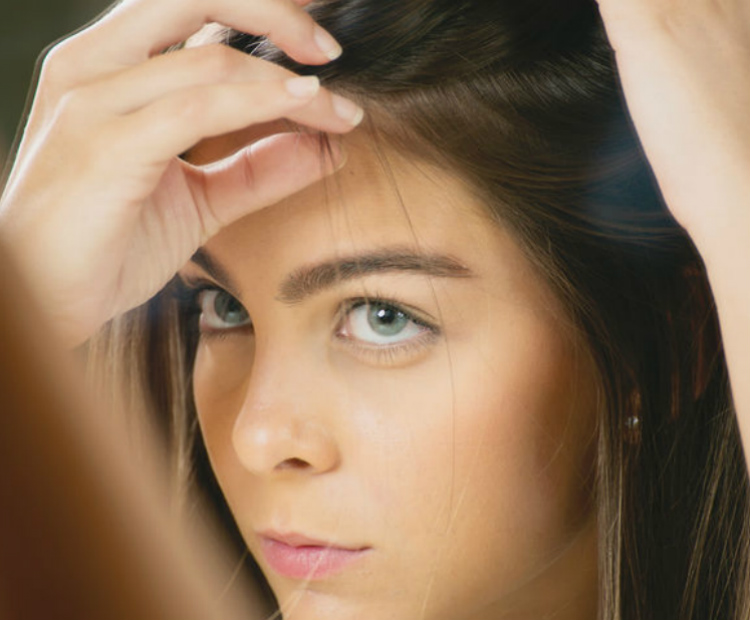 Brunette woman examining hair line