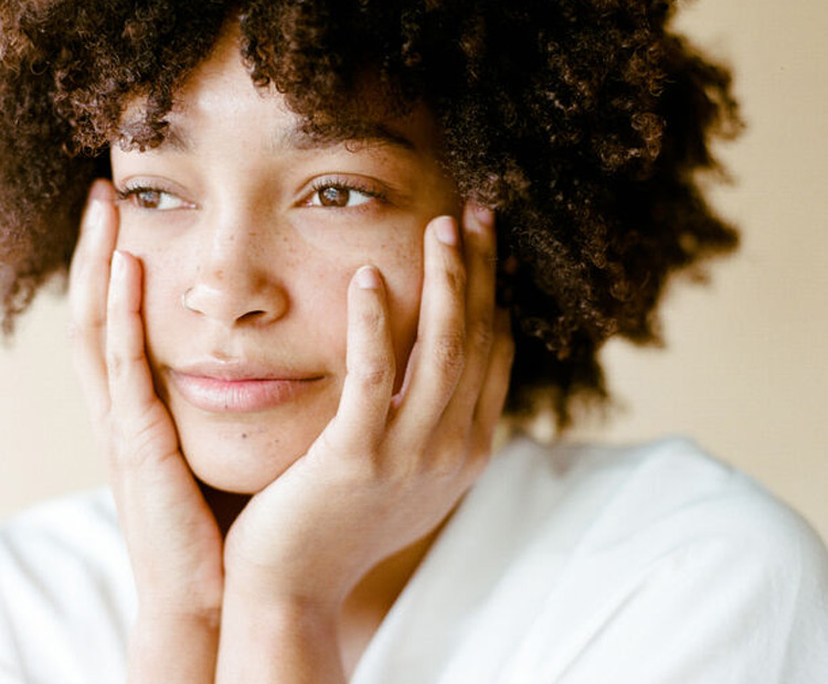 Model with freckles touching her face