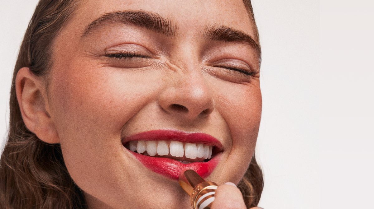 Women applying lipstick and smiling