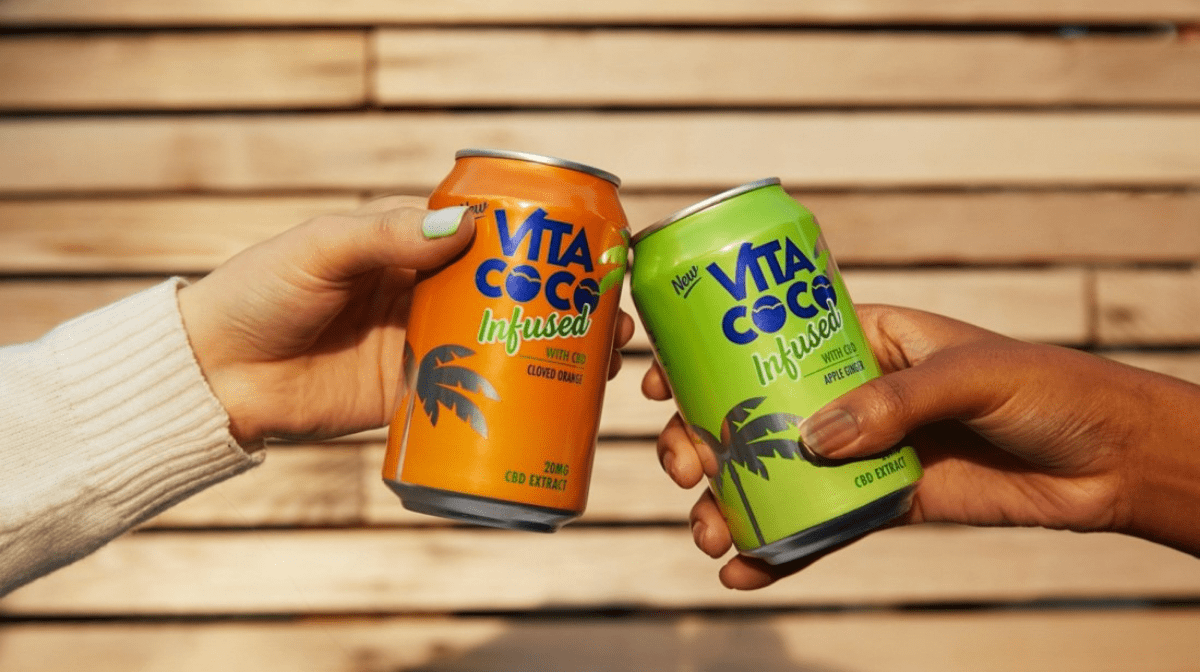 Two people clinking cans of Vita Coco Infused