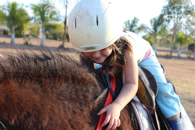 Little girl on a horse kissing their head
