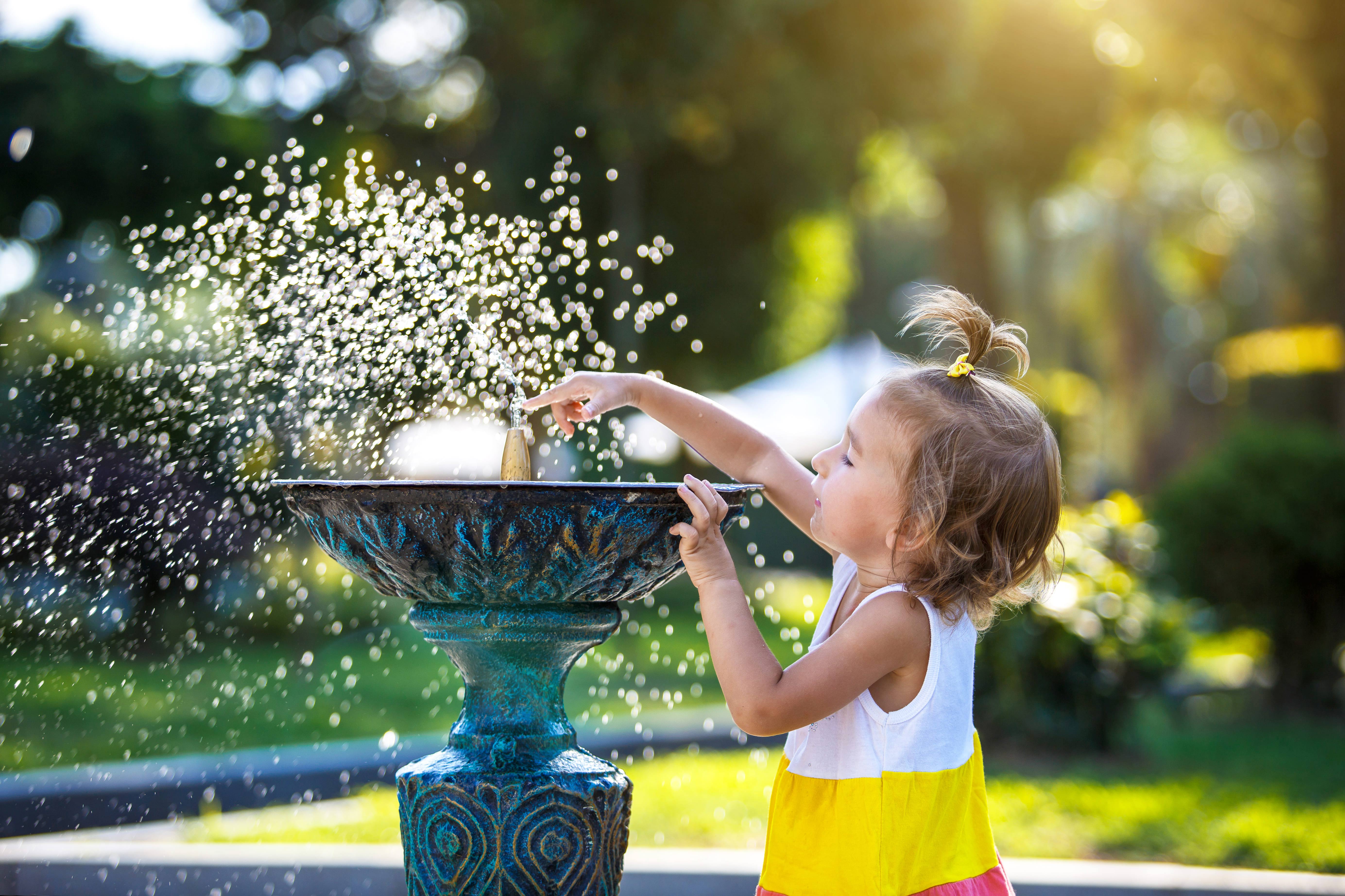 girl playing with water fountain