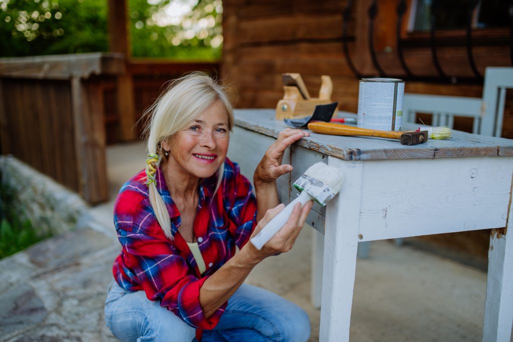 Senior Woman cleaning and renovating outdoor furniture