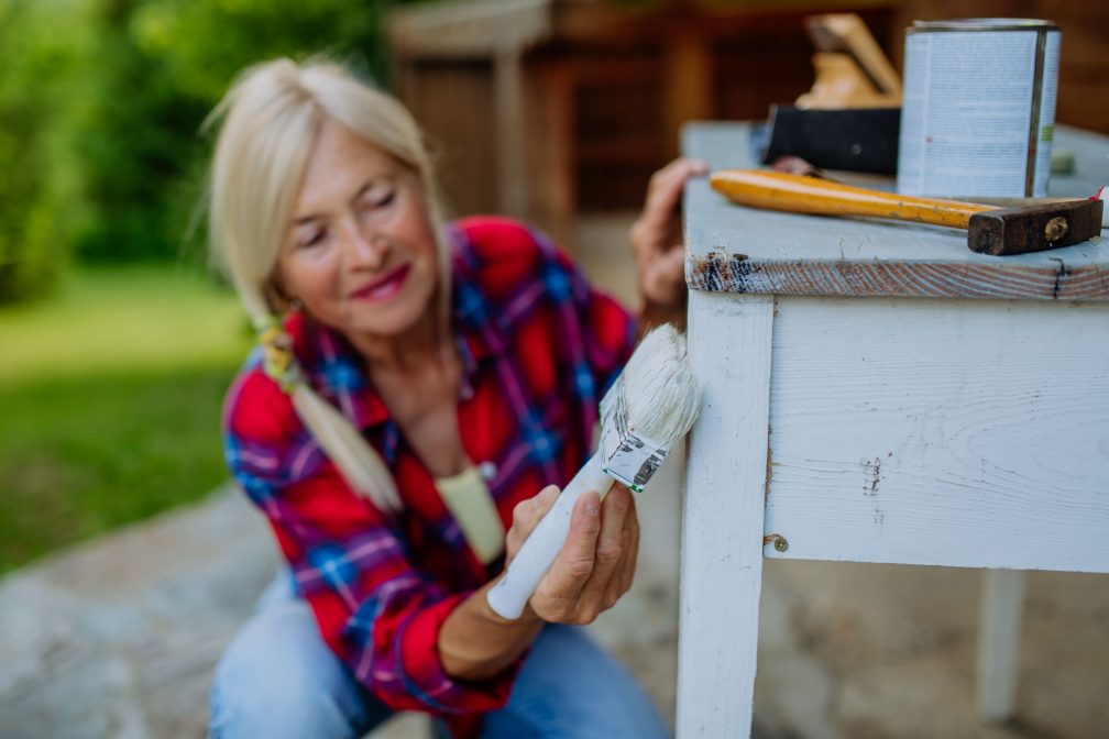 Senior Woman cleaning and renovating outdoor furniture