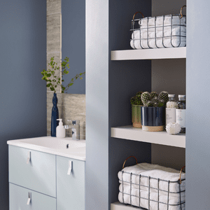 an image of wire baskets holding towels in a blue bathroom 