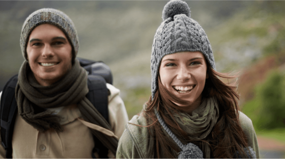 Какие пищевые добавки самые полезные в зимнее время года? женщина и мужчина, тепло одетые, поднимаются в горы и улыбаются.