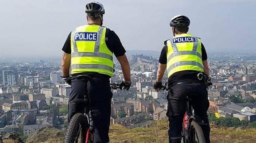 Two police cyclists stare over city below
