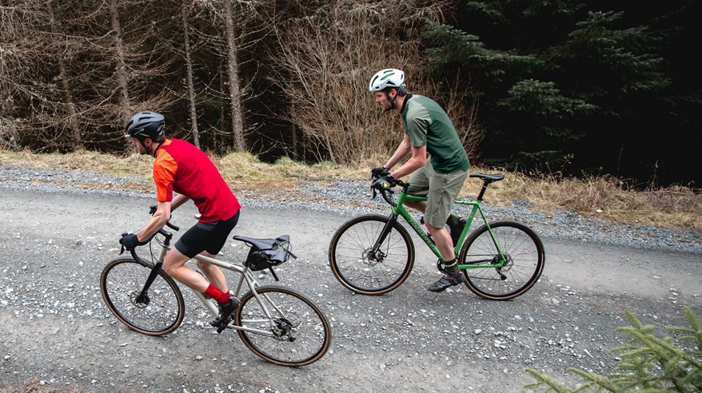 Two mountain bikers travel along a road