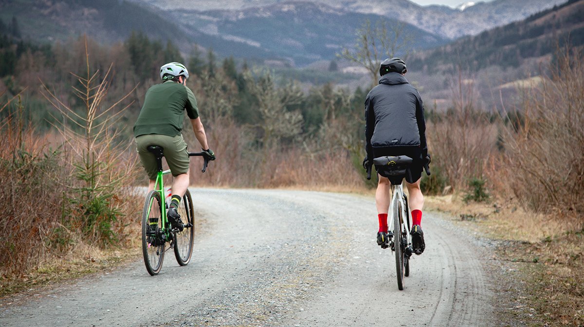 Duo of cyclists cycle along dusty road