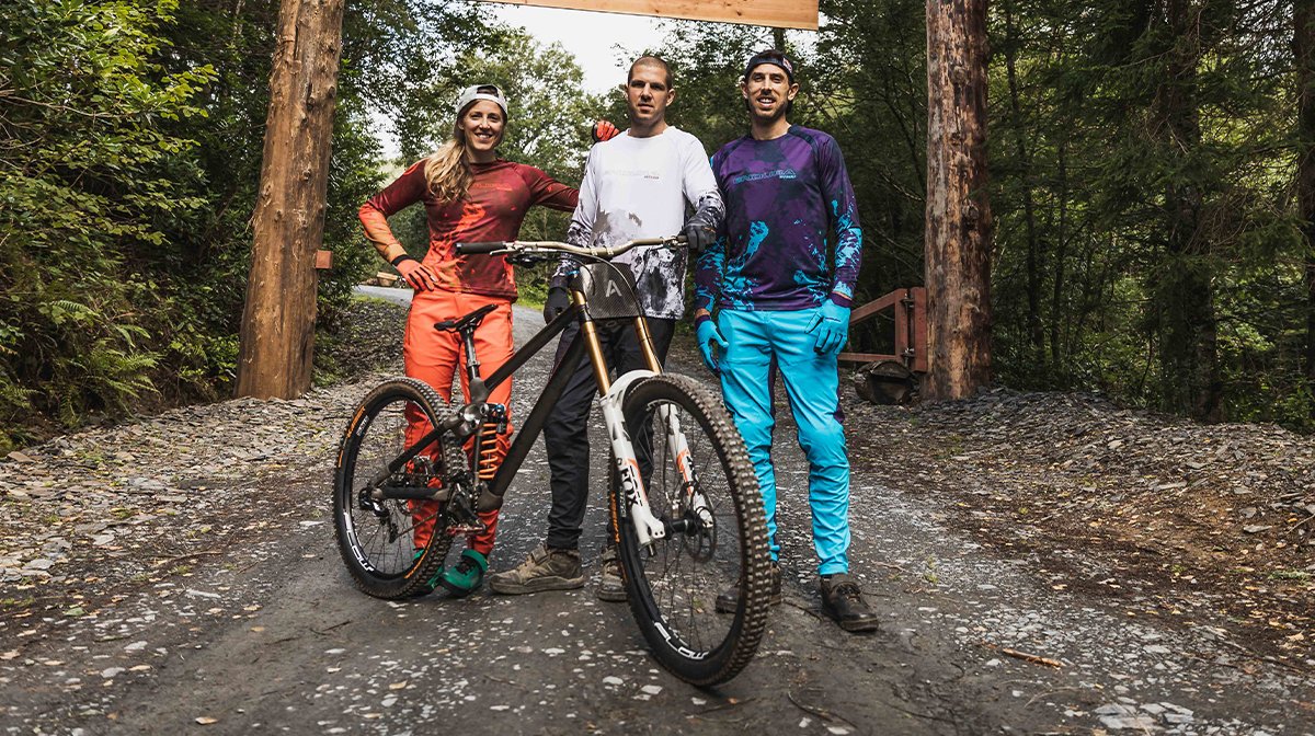 Trio stand together behind a bike, all wearing Endura MTB gear