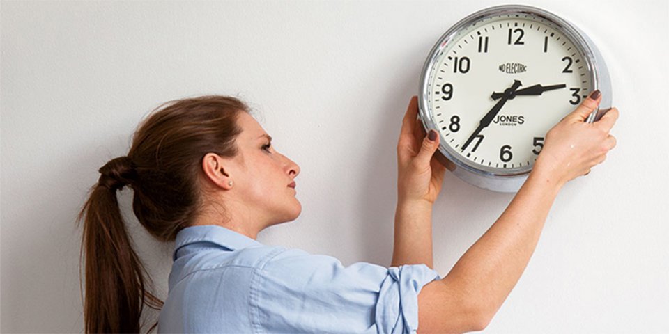 A woman fixing a clock to a wall