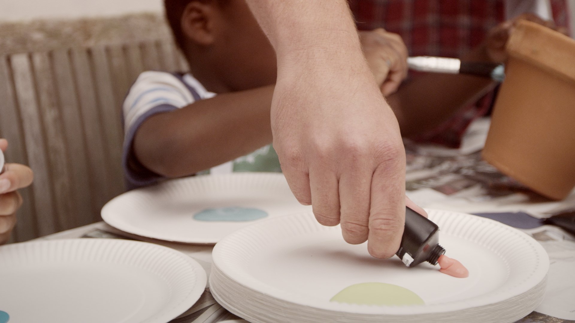 adult mixing paint colours on paper plate