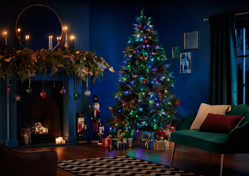 an image of a lit up Christmas tree in a blue lounge with lit candles