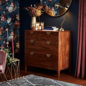 an image of a chest of drawers in a living room with wallpapered walls 