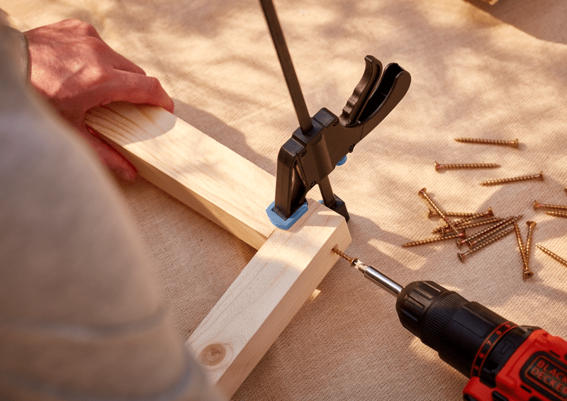 Clamp holding pieces of wood together with a drill securing it in place