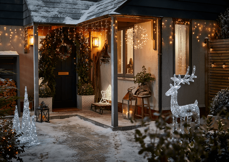 an image of a front porch with hanging christmas lights, christmas silhouette lights and a christmas wreath on the front door